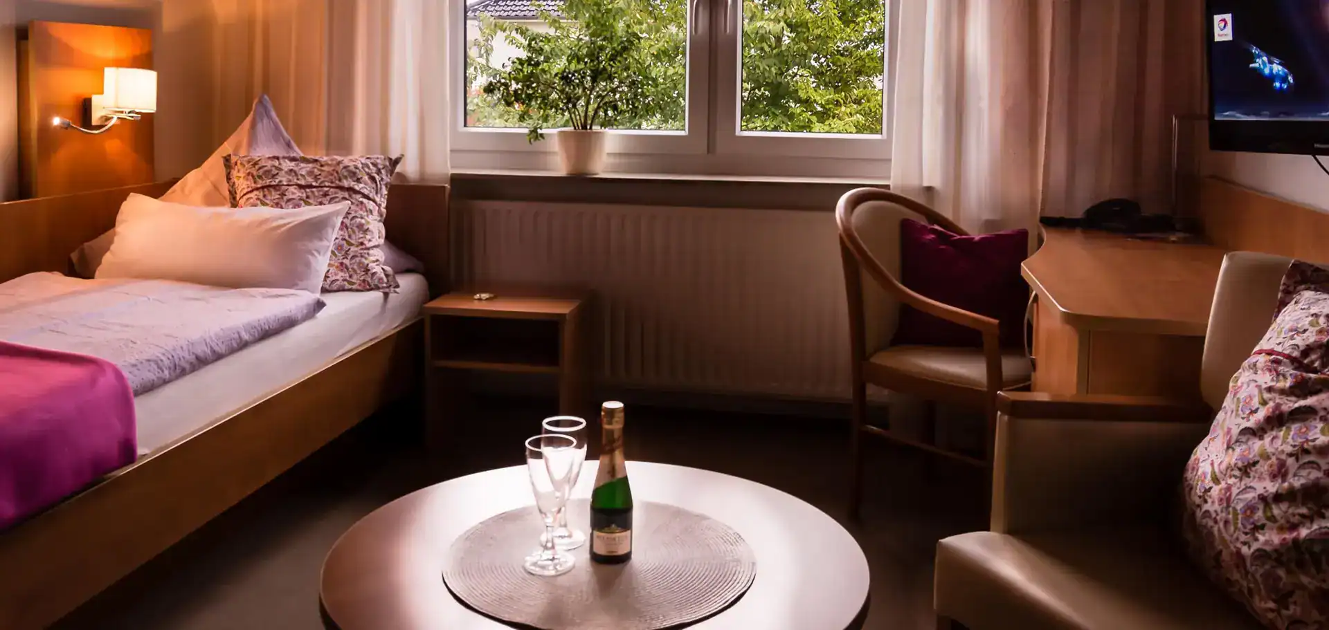A hotel room with a bed, chair and table.