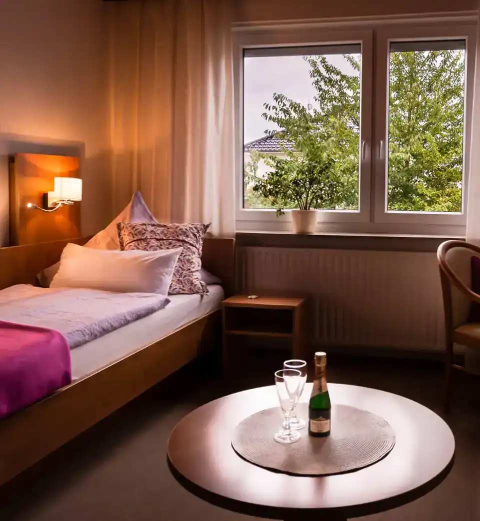 A hotel room with a bed, table and chair.